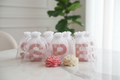Letter candles in organza gift bags on modern white marble background