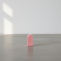 Small arch rainbow candle on grey concrete surface with white wall background