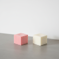 Ribbed soy cube candle on grey concrete surface with white wall background