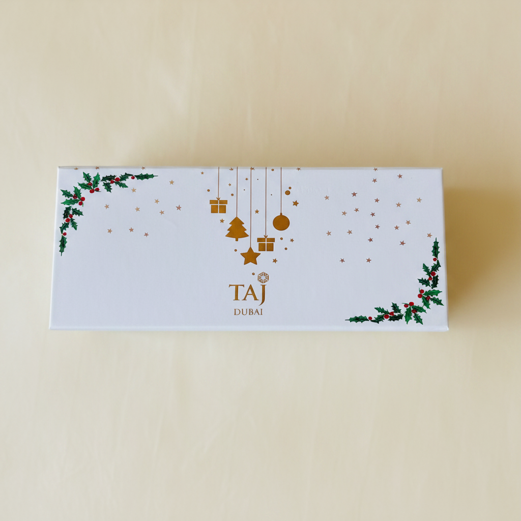 White holiday gift box with gold and holly details on warm ivory background
