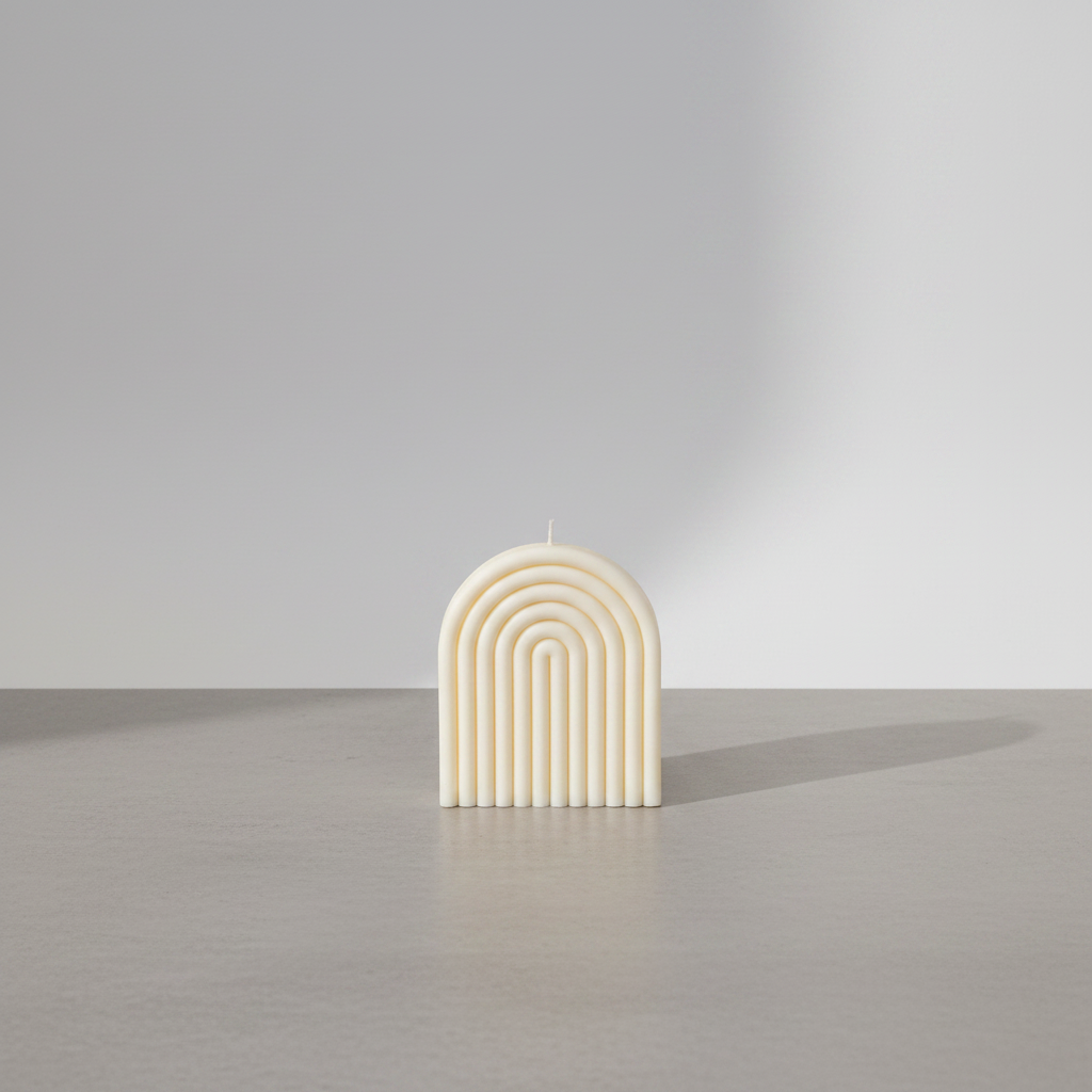 Large arch rainbow candle on grey concrete surface with white wall background